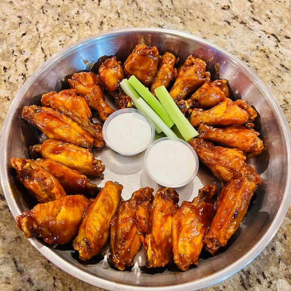 A platter of Juicy Seafood Mayport's chicken wings, celery sticks, and two dipping sauces.