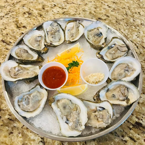 A dozen fresh oysters on the half shell, served on ice with lemon, cocktail sauce, and horseradish.